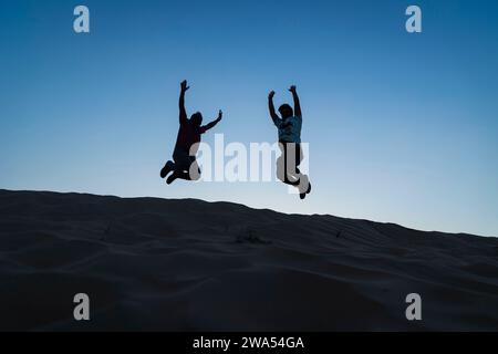 Dezember 2023, Dubai, VAE. Eine Gruppe von Leuten, die hoch über die Dünen springen. Stockfoto