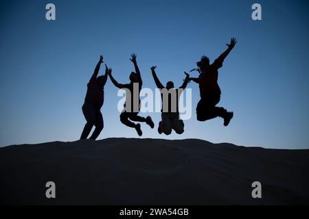 Dezember 2023, Dubai, VAE. Eine Gruppe von Leuten, die hoch über die Dünen springen. Stockfoto