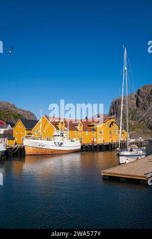 Das kleine Dorf Nusfjord an der Südküste von Lofoten, an einem hellen Sommertag, Fischerboote und Segelboote neben farbenfrohen Häusern. Stockfoto