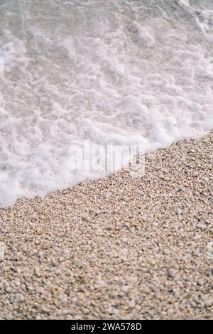 Meeressurfen rollt auf dem Kiesstrand Stockfoto