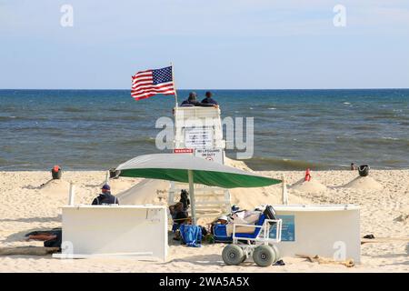 Gilgo Beach, New York, USA - 13. August 2023: Rückansicht Eines Rettungsschwimmer-Sessels am Strand mit einer amerikanischen Flagge, die im Wind weht. Stockfoto