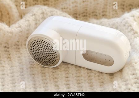 Modernes Rasiergerät aus weißem Stoff und Pullover aus heller Wolle, Nahaufnahme Stockfoto