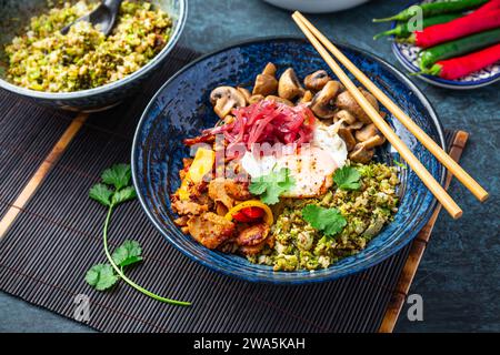 Ketogene Diät-Schüssel mit Bio-Blumenkohl und Brokkoli-Reis, gebratenem Huhn, Pilzen, Ei und Zwiebeln. Glutenfreies gesundes Essen. Stockfoto