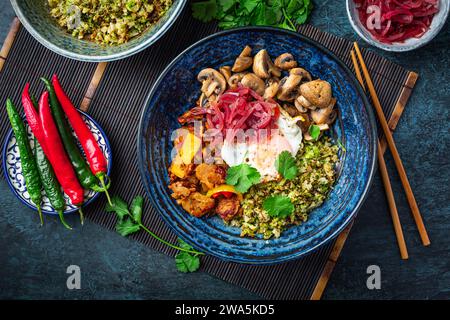 Ketogene Diät-Schüssel mit Bio-Blumenkohl und Brokkoli-Reis, gebratenem Huhn, Pilzen, Ei und Zwiebeln. Glutenfreies gesundes Essen. Stockfoto