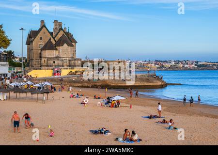 Cascais, Portugal - 14. Oktober 2023 - Menschen am Strand Praia da Duquesa und Palmela Palace in der Ferienstadt am Atlantik. Stockfoto