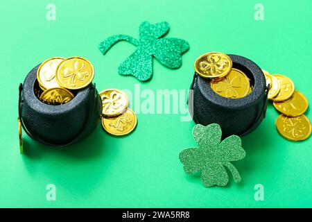 Töpfe mit Münzen und Papierkleegel auf grünem Hintergrund. St. Patrick's Day-Feier Stockfoto