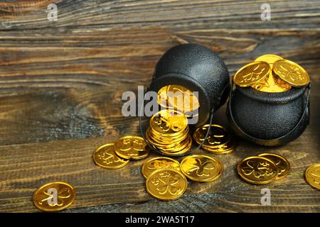 Töpfe mit goldenen Münzen auf braunem Holzhintergrund. St. Patrick's Day-Feier Stockfoto