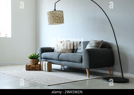 Graues Sofa mit weichen Kissen in hellem Wohnzimmer Stockfoto