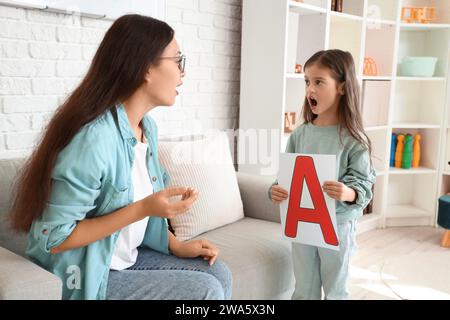 Kleines Mädchen, das den Buchstaben A ausspricht, mit einem Logopäden im Büro Stockfoto