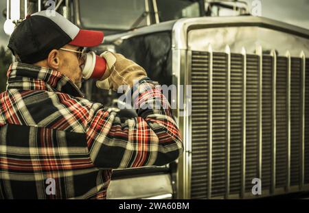 Professioneller LKW-Fahrer trinkt einen Kaffee neben seinem Semi-Truck aus der Nähe Stockfoto