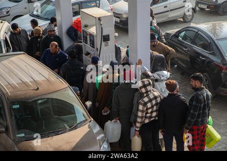 Srinagar, Indien. Januar 2024. Die Leute warten in einer Warteschlange, um an einer Tankstelle Tankdosen aufzufüllen. Tankstellen in verschiedenen indischen bundesstaaten sind Zeugen langer Warteschlangen, als Folge ständiger Proteste von Lkw- und Busfahrern im ganzen Land gegen das neue Panelgesetz über Trefferfälle. Das neu eingeführte Gesetz von Bharatiya Nyaya Sanhita, das das indische Strafgesetzbuch aus der britischen Ära aufhob, verhängt eine zehnjährige Haftstrafe und eine Geldstrafe von 184,76 US-Dollar, weil sie einem Unfallort entkommen und den Vorfall nicht gemeldet haben. (Foto: Faisal Bashir/SOPA Images/SIPA USA) Credit: SIPA USA/Alamy Live News Stockfoto