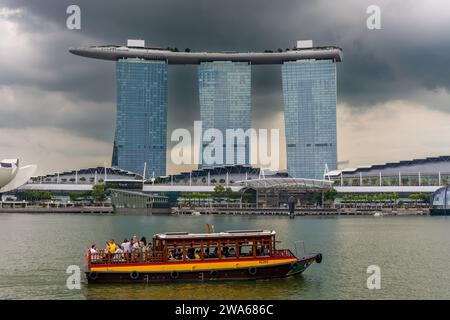 Touristenboote, die an den ikonischen Marina Bay Sands am Ufer der Stadt Singapur vorbeifahren Stockfoto