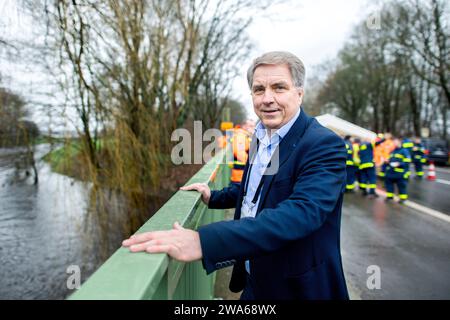 Oldenburg, Deutschland. Januar 2024. Jürgen Krogmann (SPD), Oberbürgermeister von Oldenburg und Leiter der Katastrophenschutzabteilung der Stadt, steht an einer Brücke am Osternburger Kanal, während Rettungsdienste des Bundesamtes für Technische Hilfe (THW) ein Wohngebäude vor der Überschwemmung mit Sandsäcken sichern. Nach Prognosen des Deutschen Wetterdienstes (DWD) wird mit anhaltendem Regen gerechnet, so dass die Situation in Niedersachsen weiterhin angespannt ist. Quelle: Hauke-Christian Dittrich/dpa/Alamy Live News Stockfoto