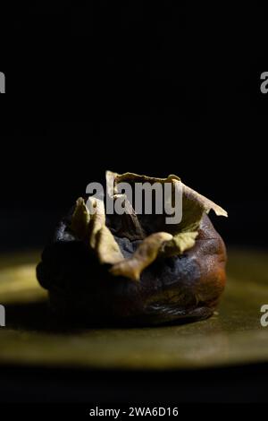 Ein altes verfallenes Persimmon auf einem Teller. Stockfoto