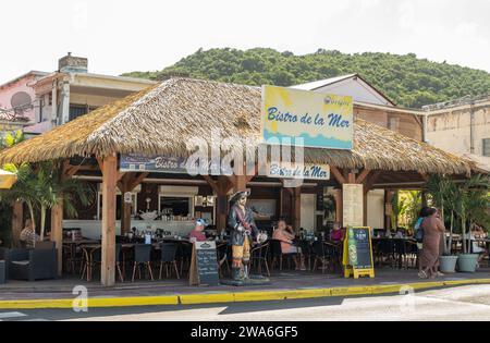 MARIGOT, SAINT MARTIN - 4. Dezember 2023: Auf der einen Seite der französischen Stadt Marigot befinden sich malerische alte Geschäfte und Marktstände. Auf der anderen Straßenseite ist dieser Mod Stockfoto