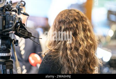 Weibliche Fernsehreporterin, die ein Mikrofon hält und ein Medieninterview macht Stockfoto