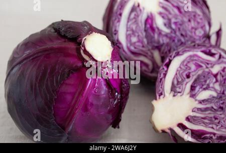 Nahaufnahme einiger Rotkohl, eine ganze und eine geteilte, auf dem Tisch angeordnet Stockfoto