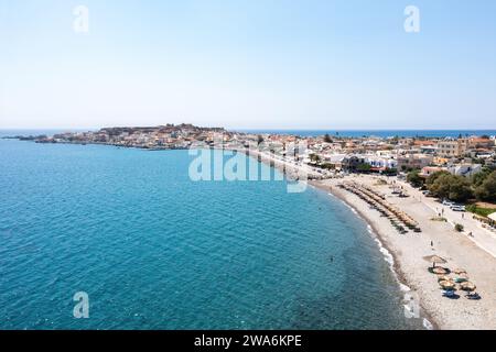 Griechenland Kreta, Kieselstrand mit Sonnenschirm in Paleochora Stadt. Luftdrohne Panoramablick auf kristallklares Meerwasser, blauen Himmel, schwimmende Menschen. Stockfoto