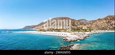 Kreta Griechenland. Drohnenblick auf den Kieselstrand mit Sonnenschirm in Palaiochora, transparentes kristallklares Meerwasser, schwimmende Menschen, felsige Formation. Stockfoto