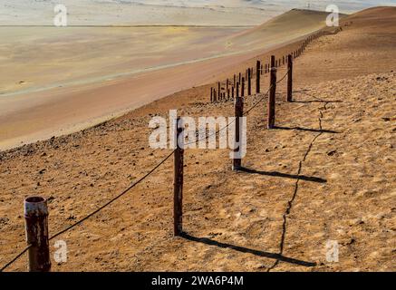 Atemberaubender Blick auf die Wüste im Paracas National Reserve mit rostigem Metallzaun, der das Naturschutzgebiet Peru begrenzt Stockfoto