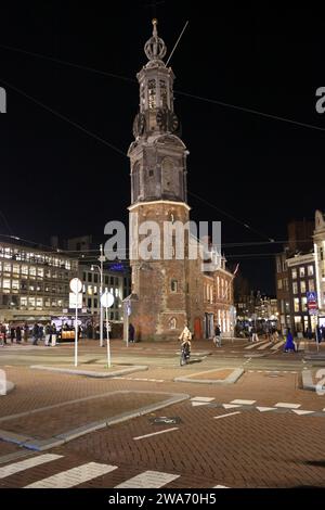 Nachtblick auf den Muntplein mit historischen Munttoren (Münzturm) in Amsterdam, mit Menschen (Radfahrer und Fußgänger) Stockfoto