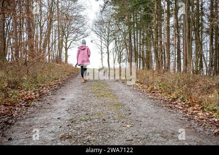 Waldspaziergang mit Hund 02.01.2024, Selters: Symbolfoto, Illustrationsbild, Symbolbild, Illustrationsfoto eine Frau, eingehüllt in warme regenfeste Kleidung, erkundet von hinten gesehen einen Waldweg, begleitet von ihrem treuen Hund. Die Szene fängt die ruhige Atmosphäre eines winterlichen nassen Waldes ein. Das harmonische Zusammenspiel von Natur und Mensch-Hund-Beziehung wird betont. Selters Hessen Deutschland *** Waldspaziergang mit Hund 02 01 2024, Selters Symbolfoto, Illustrationsfoto, Symbolfoto Eine Frau, gewickelt in warme regenfeste Kleidung, erkundet einen Waldweg aus der Nähe von Stockfoto