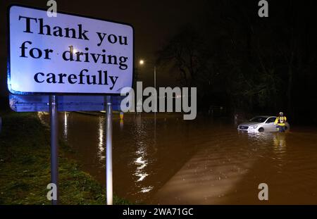 Hathern, Leicestershire, Großbritannien. Januar 2024. Wetter in Großbritannien. Ein Feuerwehrmann überprüft ein Auto, das im Hochwasser gestrandet ist. Starke Winde und heftige Regenfälle treffen einen großen Teil Großbritanniens, als der kleine, aber potente Sturm Henk trifft. Credit Darren Staples/Alamy Live News. Stockfoto