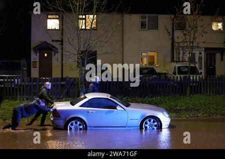 Hathern, Leicestershire, Großbritannien. Januar 2024. Wetter in Großbritannien. Autofahrer schieben ein Auto, nachdem sie in Hochwasser gestrandet sind. Starke Winde und heftige Regenfälle treffen einen großen Teil Großbritanniens, als der kleine, aber potente Sturm Henk trifft. Credit Darren Staples/Alamy Live News. Stockfoto