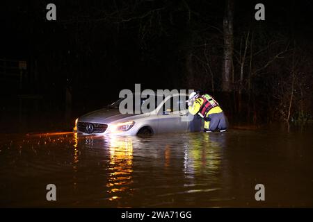 Hathern, Leicestershire, Großbritannien. Januar 2024. Wetter in Großbritannien. Ein Feuerwehrmann überprüft ein Auto, das im Hochwasser gestrandet ist. Starke Winde und heftige Regenfälle treffen einen großen Teil Großbritanniens, als der kleine, aber potente Sturm Henk trifft. Credit Darren Staples/Alamy Live News. Stockfoto