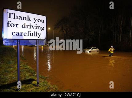 Hathern, Leicestershire, Großbritannien. Januar 2024. Wetter in Großbritannien. Ein Feuerwehrmann überprüft ein Auto, das im Hochwasser gestrandet ist. Starke Winde und heftige Regenfälle treffen einen großen Teil Großbritanniens, als der kleine, aber potente Sturm Henk trifft. Credit Darren Staples/Alamy Live News. Stockfoto