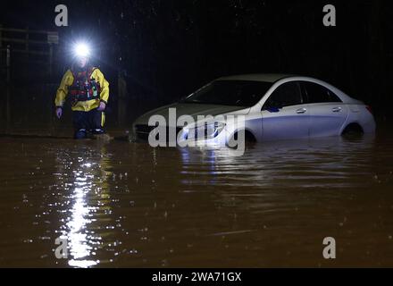 Hathern, Leicestershire, Großbritannien. Januar 2024. Wetter in Großbritannien. Ein Feuerwehrmann überprüft ein Auto, das im Hochwasser gestrandet ist. Starke Winde und heftige Regenfälle treffen einen großen Teil Großbritanniens, als der kleine, aber potente Sturm Henk trifft. Credit Darren Staples/Alamy Live News. Stockfoto