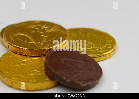 Ein Nahfoto goldener Schokoladenmünzen auf einer weißen Schreibtischoberfläche. Stockfoto