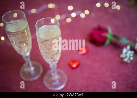 valentinstag Gläser Champagner, Schokolade, eine rote Rose und einige Lichter im Hintergrund Stockfoto