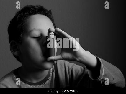 Kind mit Grippe mit Inhalator Atemschutz auf grauem Hintergrund mit Menschen Stockfoto Stockfoto