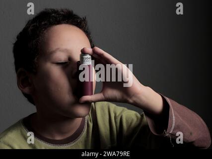 Kind mit Grippe mit Inhalator Atemschutz auf grauem Hintergrund mit Menschen Stockfoto Stockfoto