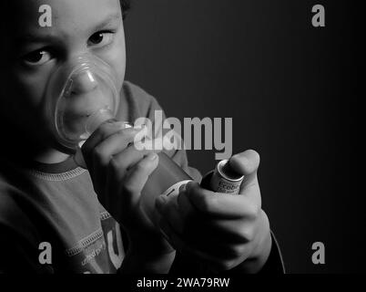 Kind mit Grippe mit Inhalator Atemschutz auf grauem Hintergrund mit Menschen Stockfoto Stockfoto