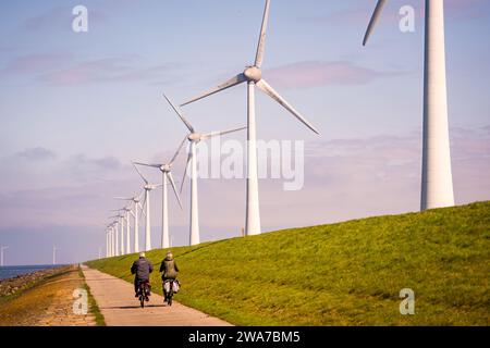 Menschen, die auf der Straße in der Nähe von Windturbinen Fahrrad fahren Stockfoto