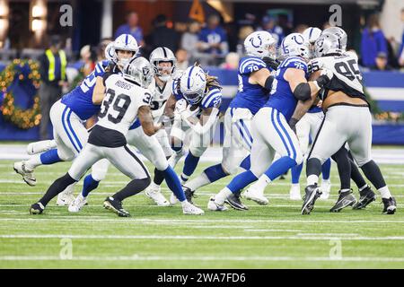 Indianapolis, Indiana, USA. Dezember 2023 31. Die Indianapolis Colts Running Back Trey Sermon (27) läuft mit dem Ball, als die Las Vegas Raiders Defensivback Nate Hobbs (39) im Lucas Oil Stadium in Indianapolis, Indiana, den Angriff übernimmt. John Mersits/CSM/Alamy Live News Stockfoto