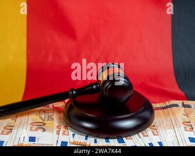 Der Hammer des Richters liegt auf 50-Euro-Scheinen vor dem Hintergrund der deutschen Flagge. Recht und Gerechtigkeit. Stockfoto