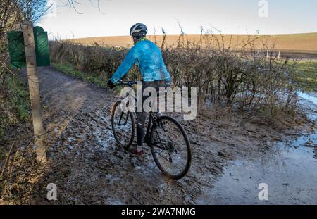 Weibliche Radfahrerin, die auf einer nassen und schlammigen Strecke fährt. Stockfoto