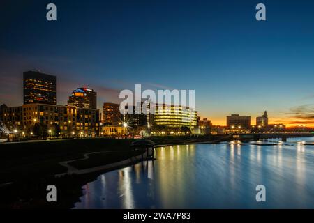 Skyline von Dayton bei Sonnenuntergang. Miami River im Vordergrund. Dayton, Ohio, USA. Stockfoto