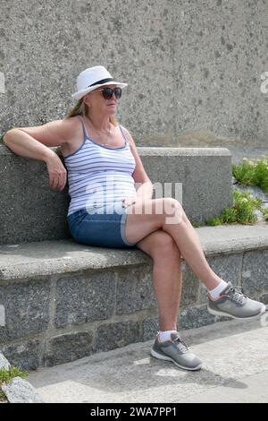 Eine Dame, die sich im Hafen von Carentan in der Normandie, Frankreich, Europa während des langen heißen Sommers 2022 entspannt Stockfoto