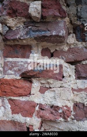 Nahaufnahme eines urbanen strukturierten, beschädigten und geschliffenen alten Ziegelsteins mit Mörtel und Zement schöne Tapeten, Hintergrund, strukturelle Muster Stockfoto