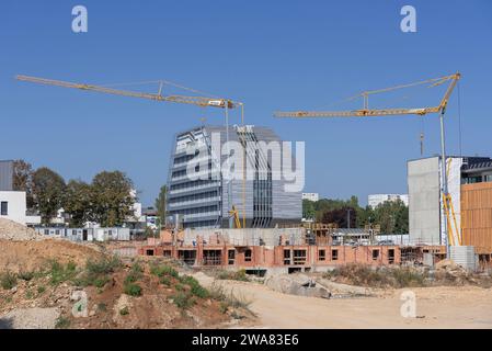 Selbstaufrichtende Krane Potain Hup 40-30 und IGO 50 auf einer Baustelle und einem Gebäude im Bau mit einem modernen Gebäude im Hintergrund. Stockfoto