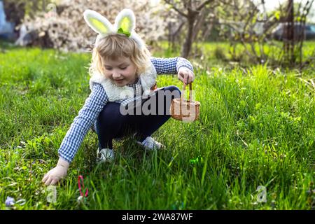 Kleines Mädchen sammelt bunte Ei im Park. Konzept der Osterjagd Stockfoto