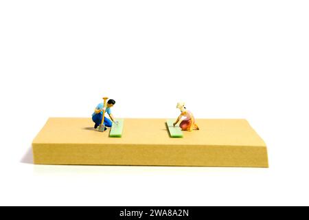 Kreative Miniaturmenschen spielzeugfiguren fotografieren. Installation von Haftnotizen. Ein Paar, das im Sommerurlaub Gartenarbeit im Hof macht. Isoliert am Stockfoto
