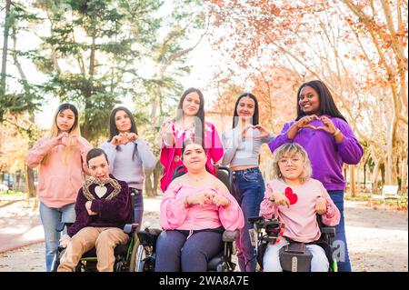 Internationaler Frauentag Inspiire Inspired Inclusion multiethnische Gruppen lieben Herz mit Händen. Rollstuhl Stockfoto