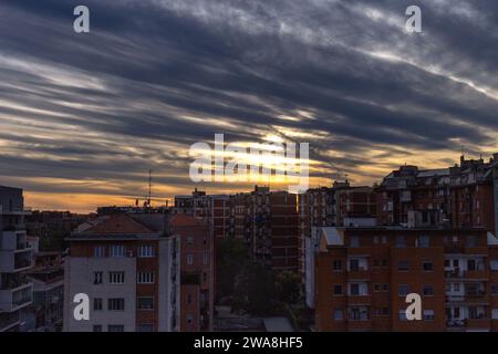 Die Skyline der Stadt wird zu einer atemberaubenden Silhouette, während die dramatischen Farbtöne eines feurigen Sonnenuntergangs den Himmel über den Gebäuden prägen. Stockfoto