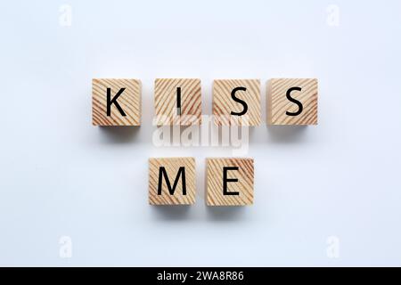 Holzwürfel mit Phrase Kiss mich auf weißem Hintergrund, flach Stockfoto