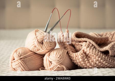 Strickgarn, Nadeln, grober Pullover. Gemütliches, gemütliches Ambiente. Garn in warmen Farben von Pfirsich, Beige. Stricken als Hobby. Strickzubehör. Stockfoto